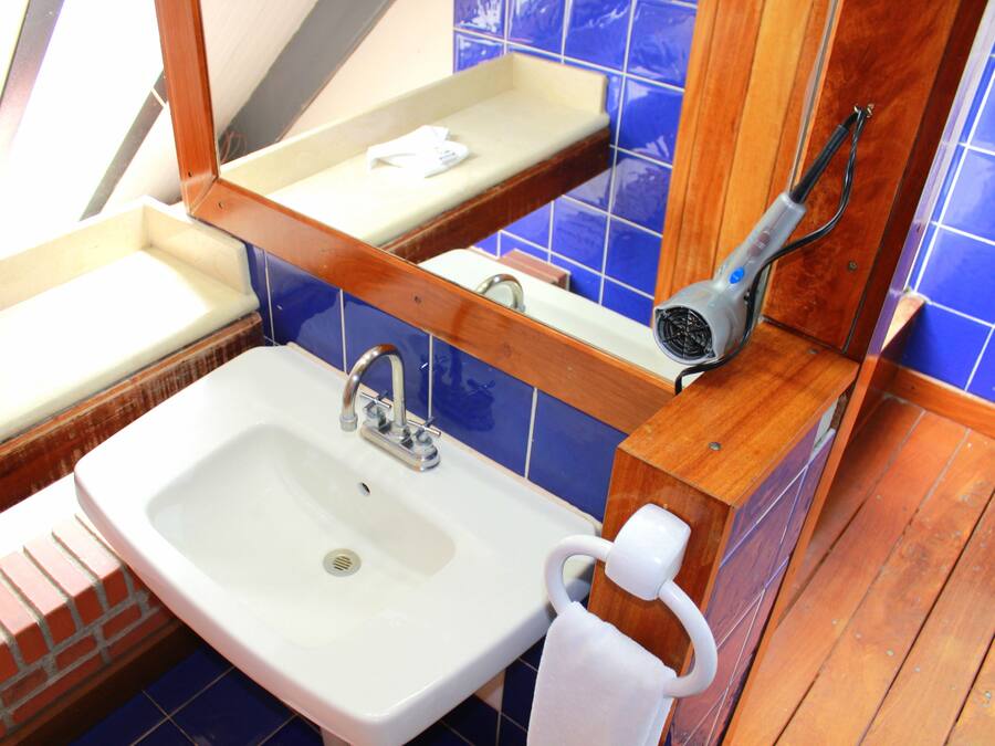A bathroom with a white sink, a mirror, a towel rack, and a hairdryer.