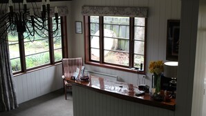 Een keuken met een houten aanrecht, een stoel, een raam met uitzicht op groen en een kroonluchter.