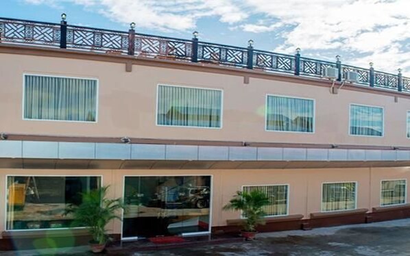 A two-story building with large windows and a balcony with a metal railing.