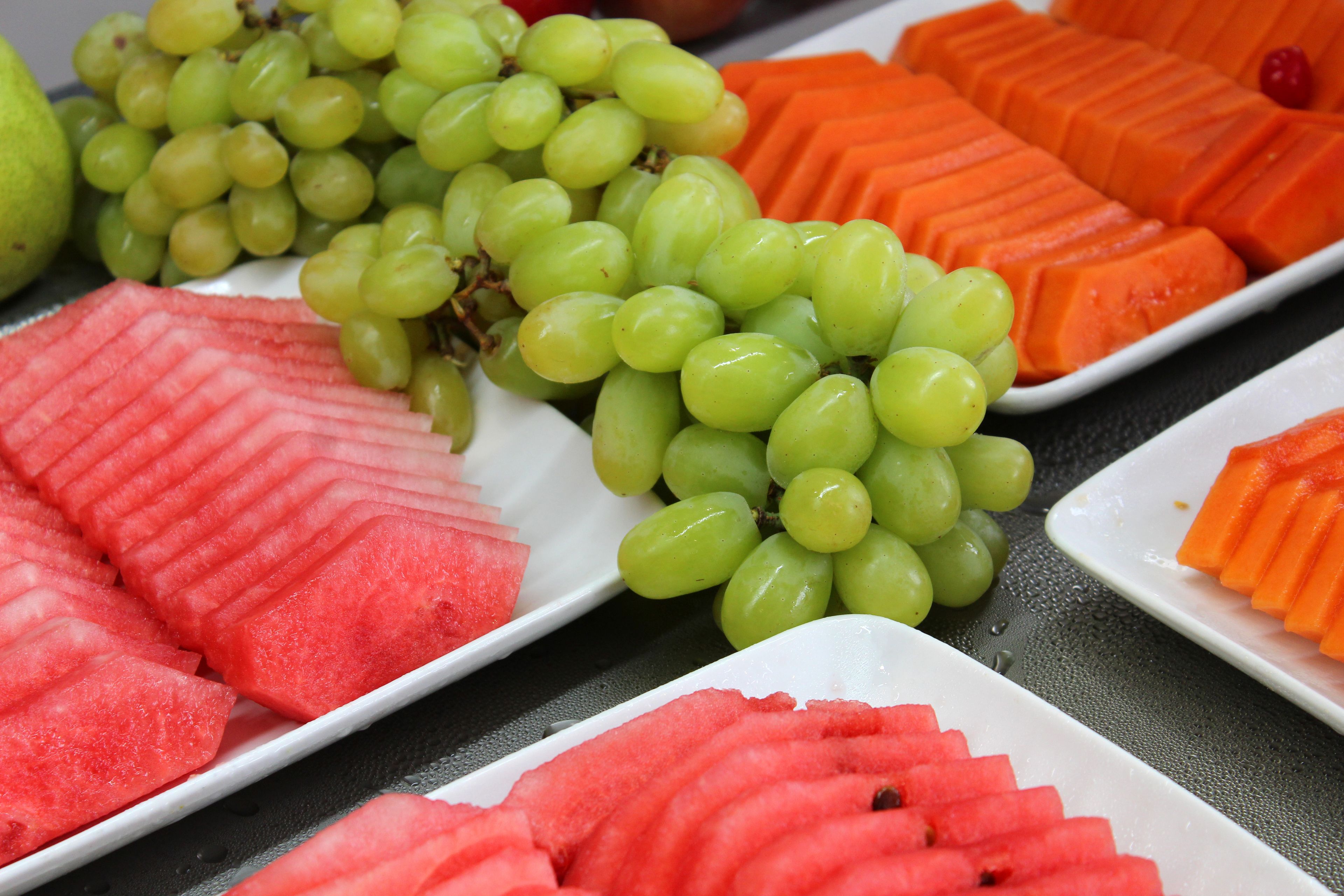 Diversas frutas, incluindo melancia, uvas e fatias de laranja, dispostas em pratos.