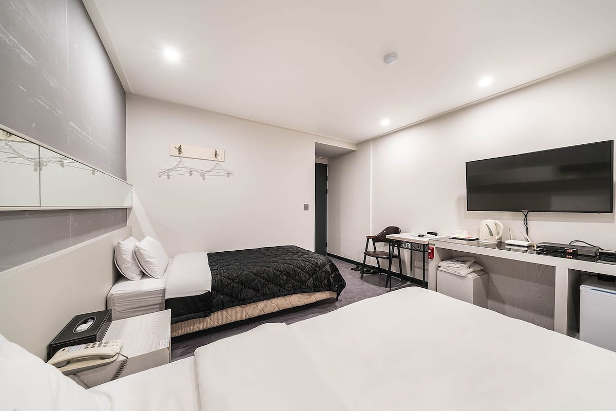 Habitació d'hotel amb llit, escriptori, televisió i una cuineta petita.