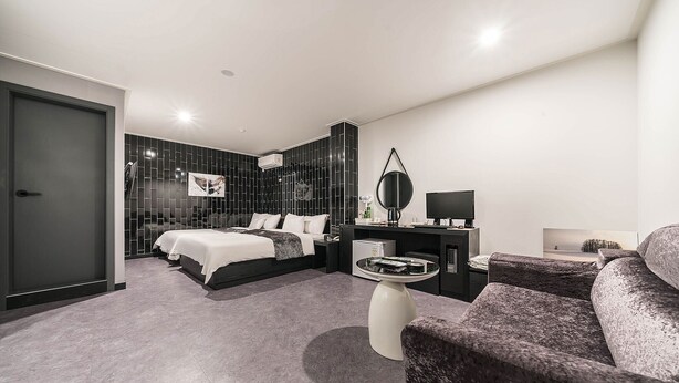 Una habitación de hotel moderna con una cama, un escritorio, una silla y una mesita.