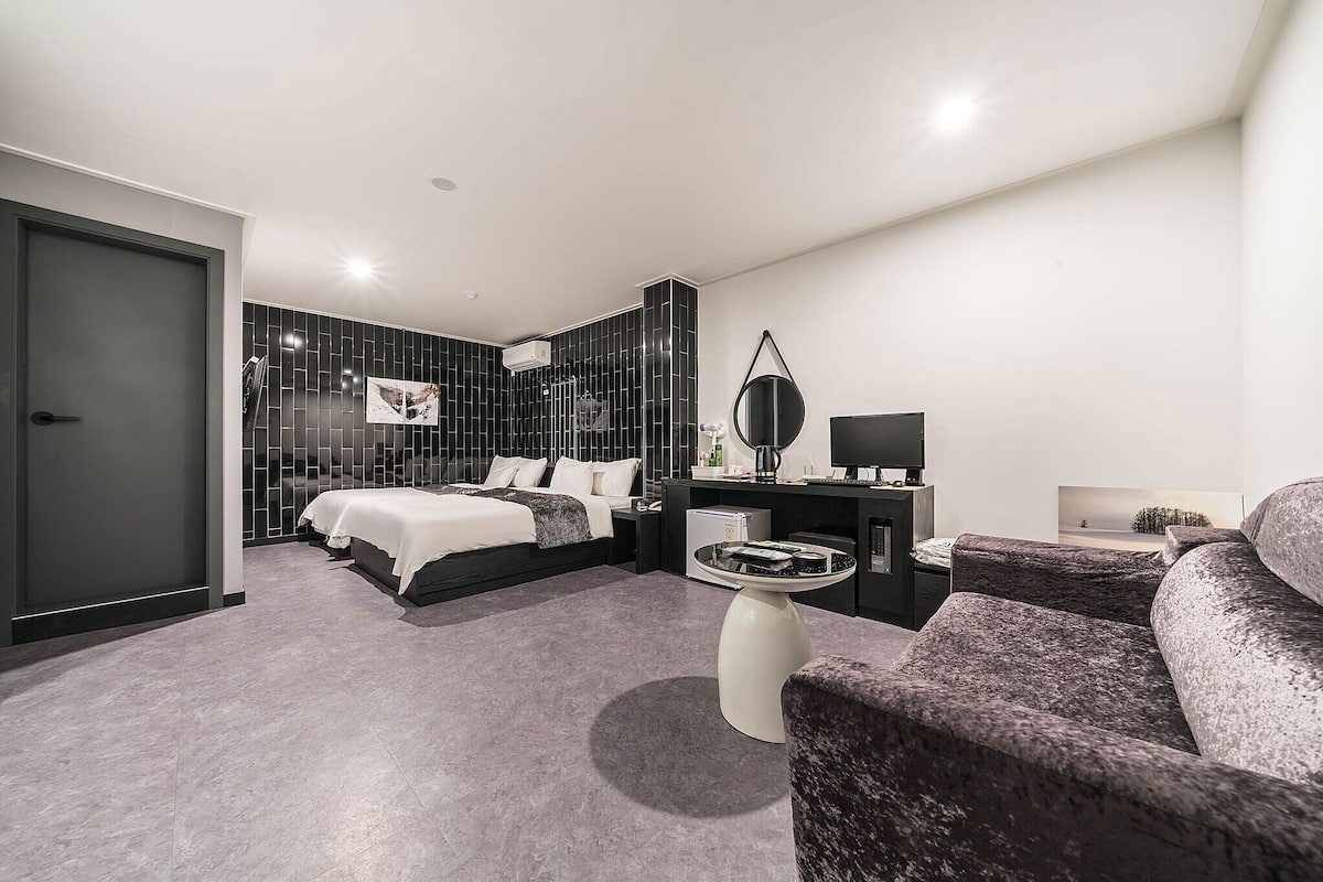 Habitació d'hotel moderna amb llit, escriptori, cadira i taula petita.