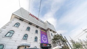 Un edificio de hotel con el letrero "HOTEL LINE" y un banderín anunciando "GRAN APERTURA".