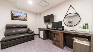 Una habitación moderna con sofá, escritorio, computadora y un espejo grande.