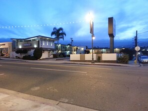 A motel with a modern design, featuring a two-story structure, a parking area, and a street view with string lights. - The Guest Harbor Inn - Port of Los Angeles San Pedro (San Pedro)