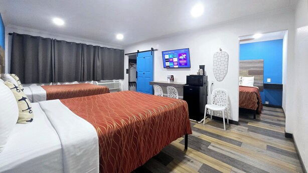Habitación de hotel con dos camas, un escritorio con computadora, televisor y armario.