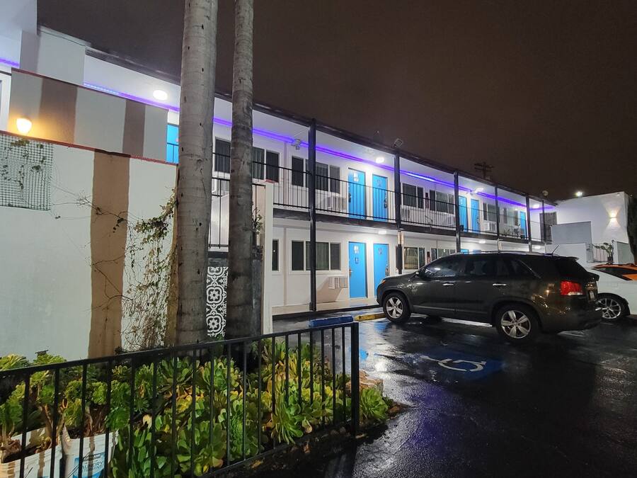 A multi-story building with a parking area and a car parked in front.