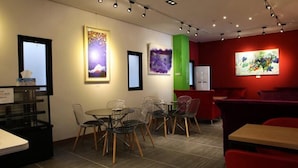 A modern restaurant with a red accent wall, contemporary art, and a mix of metal and wooden furniture. - Line Plus Hotel (Gimpo)