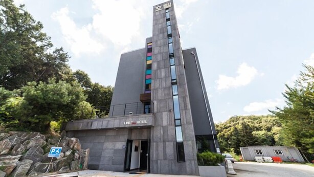 A modern hotel with a tall, rectangular structure and a sign indicating it is a hotel. - Line Plus Hotel (Gimpo)