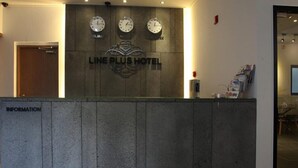 A reception desk at the LINE PLUS HOTEL with clocks and a sign indicating the hotel's name. - Line Plus Hotel (Gimpo)
