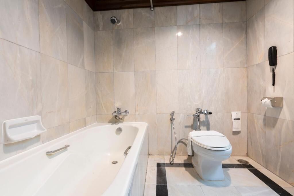 A modern bathroom with a bathtub, toilet, and shower.