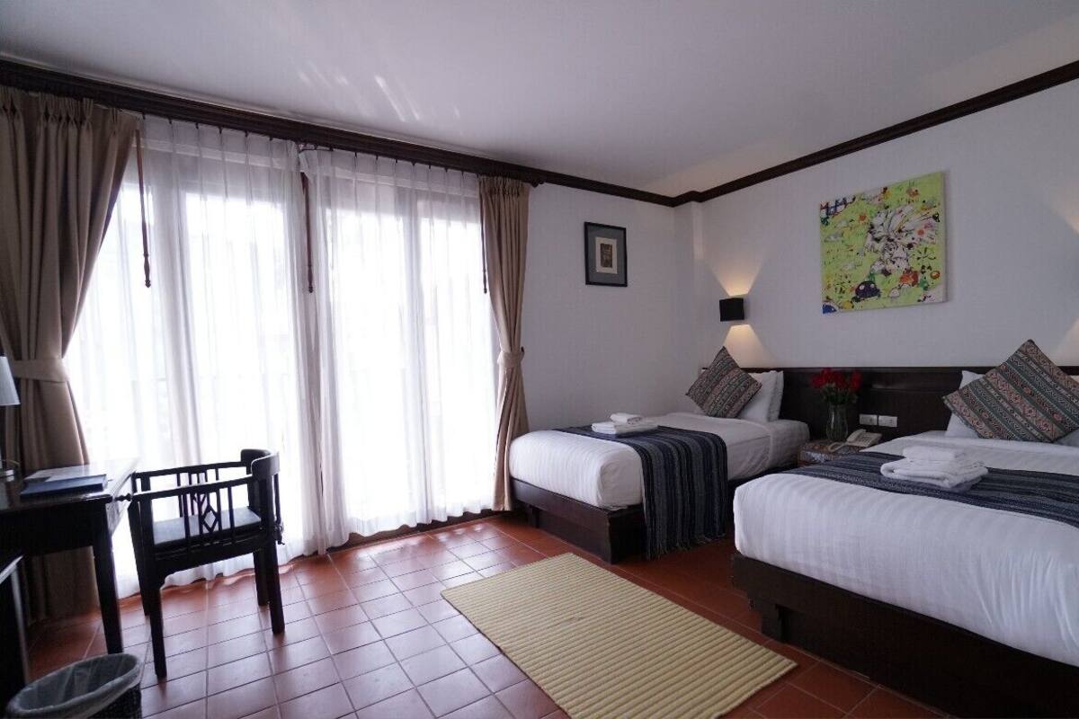 Une chambre d’hôtel avec deux lits, un bureau et une chaise.