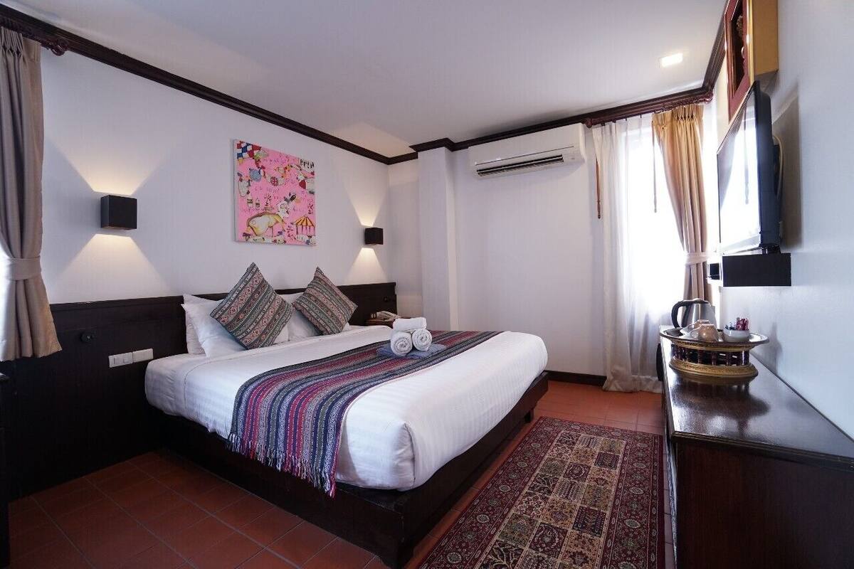 Une chambre d’hôtel dotée d’un grand lit, d’une télévision à écran plat, d’un système de climatisation et d’un tapis décoratif.