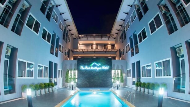 A modern hotel with a central swimming pool, multiple balconies, and a neon sign. - The Peak Boutique Hotel (Phra Phrom)