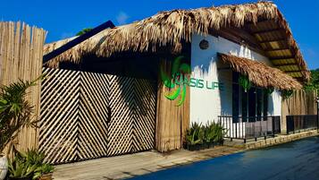 A building with a thatched roof, a bamboo fence, and a sign reading "COAST LIME".