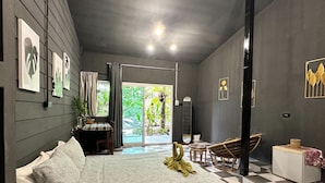Quarto moderno com piso quadriculado, cama com roupa de cama estampada, uma mesinha e uma cadeira.