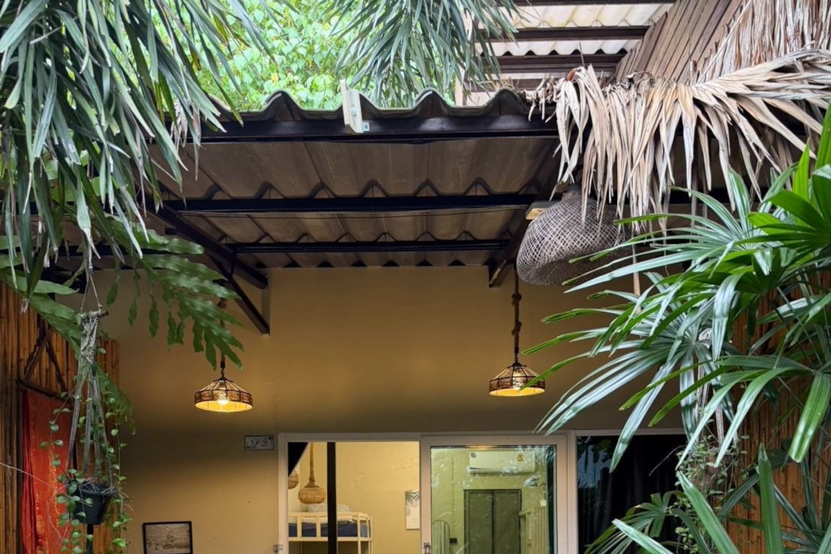 Una entrada de estilo tropical con suelo de madera, una cama y un suelo a cuadros que conduce a una puerta de cristal.