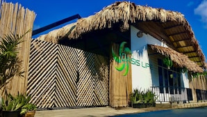 Um edifício com fachada de bambu e telhado de palha, exibindo o logotipo 'Crisis Life'.