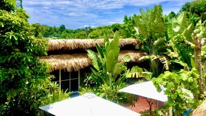Um jardim exuberante com construções de palha e plantas tropicais.