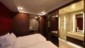 Habitación de hotel con cama, zona de ducha y un espejo grande.