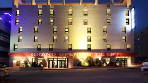 Un edificio de hotel con un letrero que dice "Benika The H Hotel" y un cartel anunciando "Gran Inauguración 12.15".