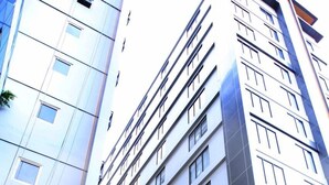 Un hotel moderno de varios pisos con fachada limpia y geométrica y grandes ventanales.
