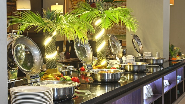 Un bufé con diversos alimentos y utensilios, que incluye cuencos, platos y una piña como centro de mesa.