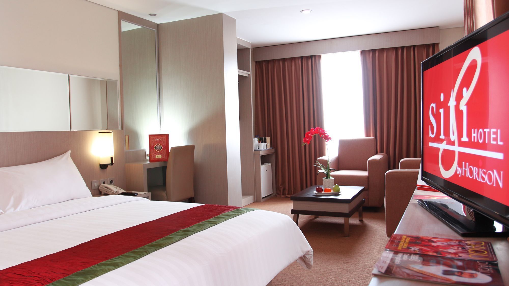 A hotel room with a bed, a desk, a television, and a window with curtains.