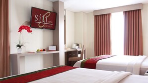 Habitación de hotel con dos camas, un escritorio con silla, un televisor mostrando 'Siti Hotel by Horizon', un calendario y una ventana con cortinas.
