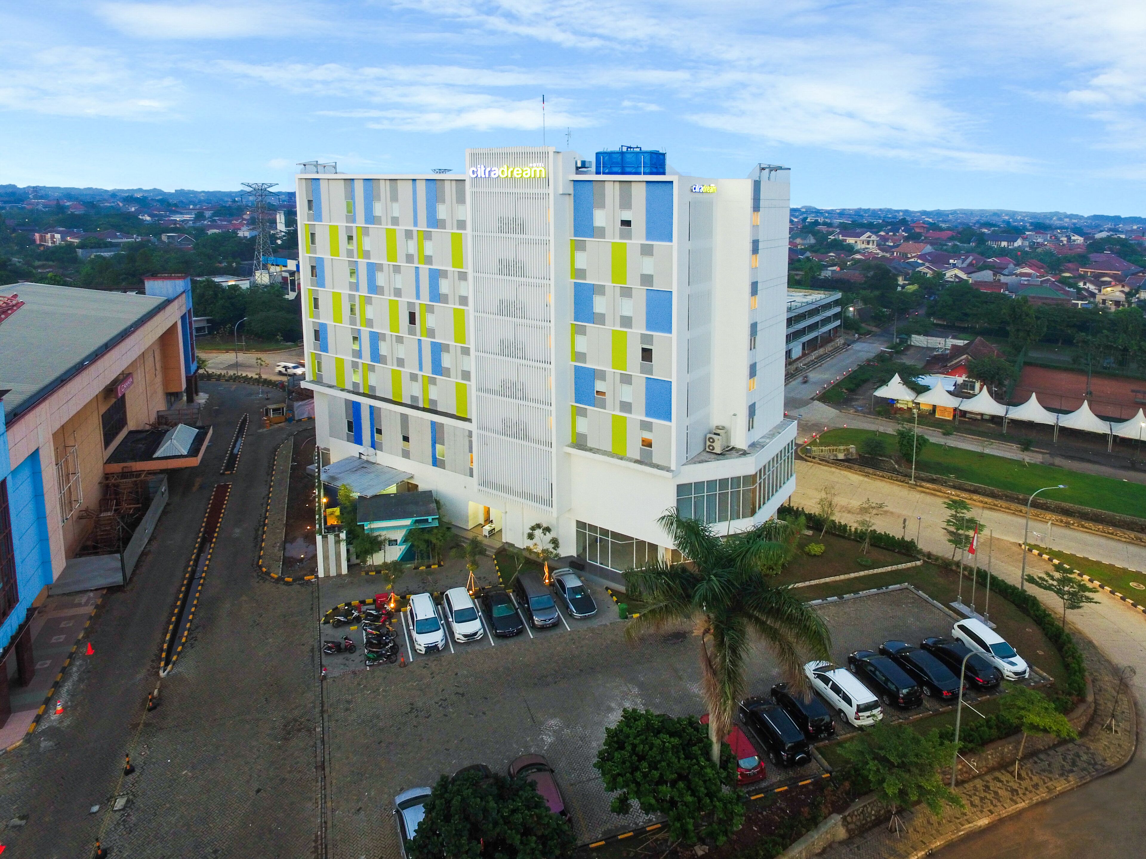 A modern hotel with a multi-story structure, a parking lot, and a view of the surrounding cityscape.