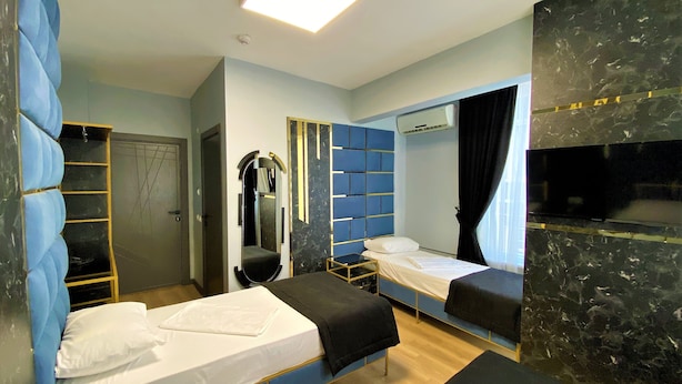 A hotel room with two single beds, a wardrobe, a mirror, a television, and a ceiling light. - Orange Airport Hotel (Istanbul)