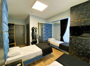 A hotel room with two single beds, a wardrobe, a mirror, a television, and a ceiling light. - Orange Airport Hotel (Istanbul)