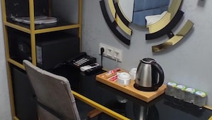A compact workspace with a desk, chair, and a hanging coat rack. - Orange Airport Hotel (Istanbul)