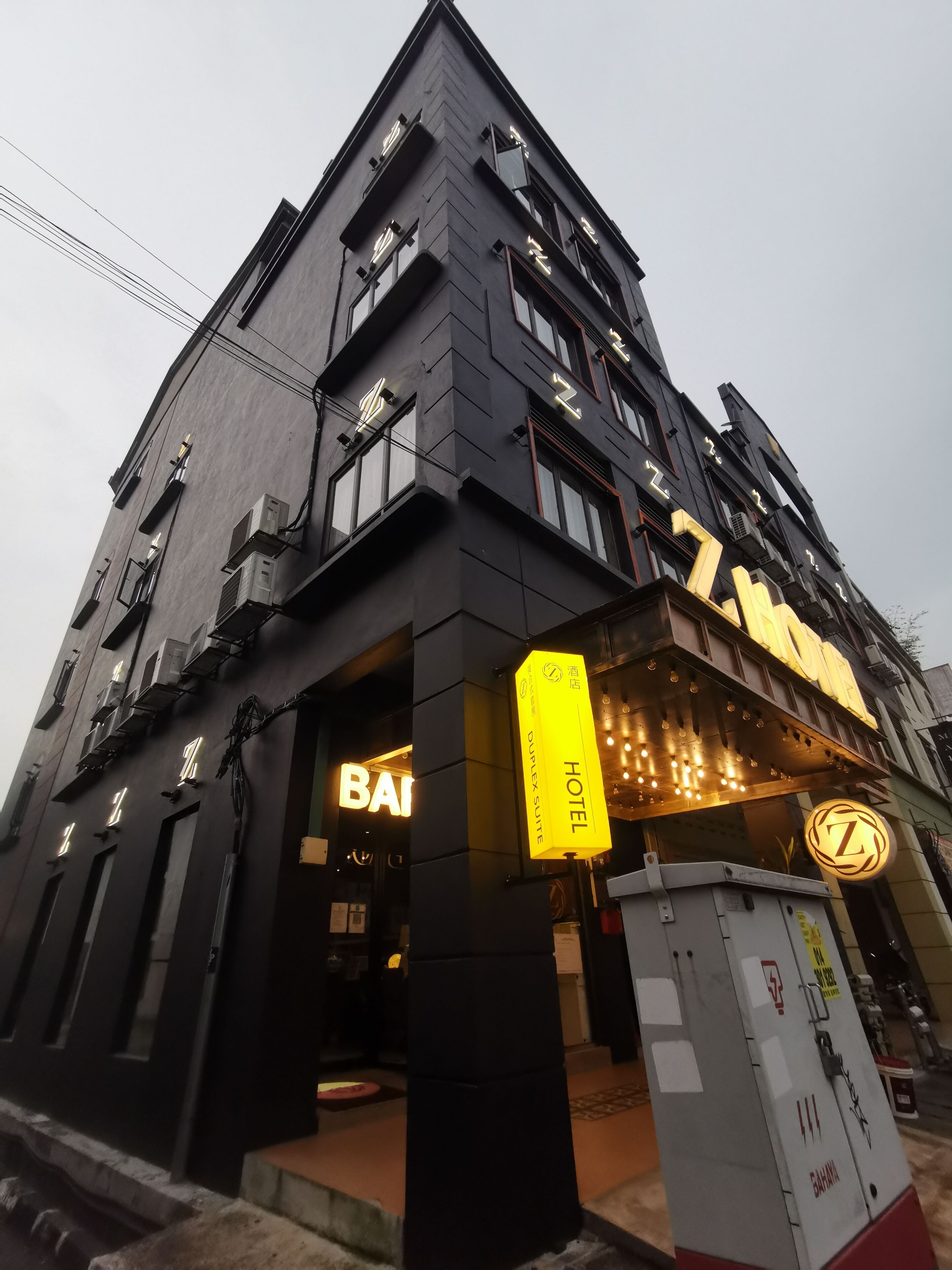 Een modern hotel met een opvallend 'HOTEL' bord, een 'BAI' bord en een 'DUPLEX SUITE' bord.