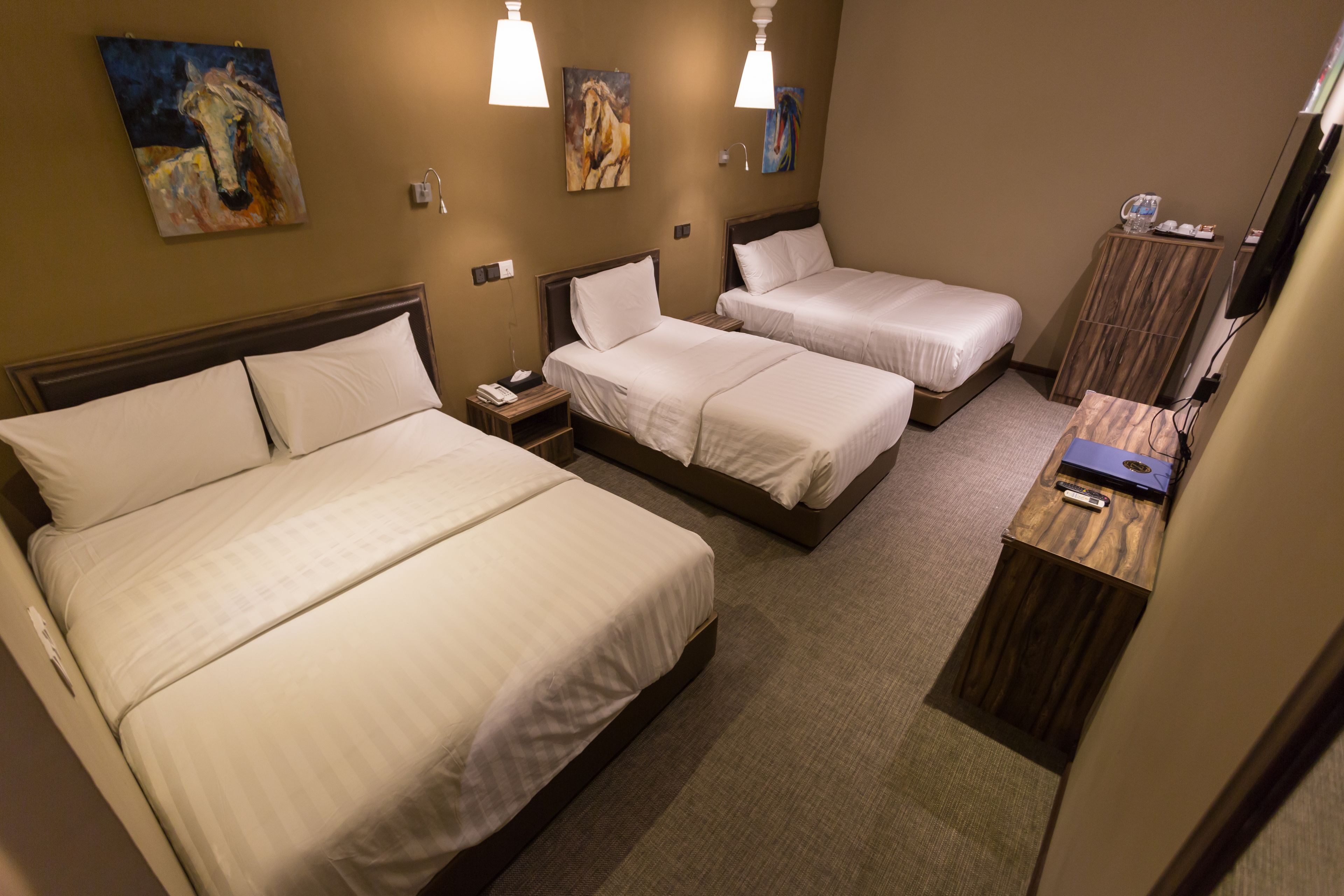 A hotel room with two beds, a wooden nightstand, a desk, and a mirror.