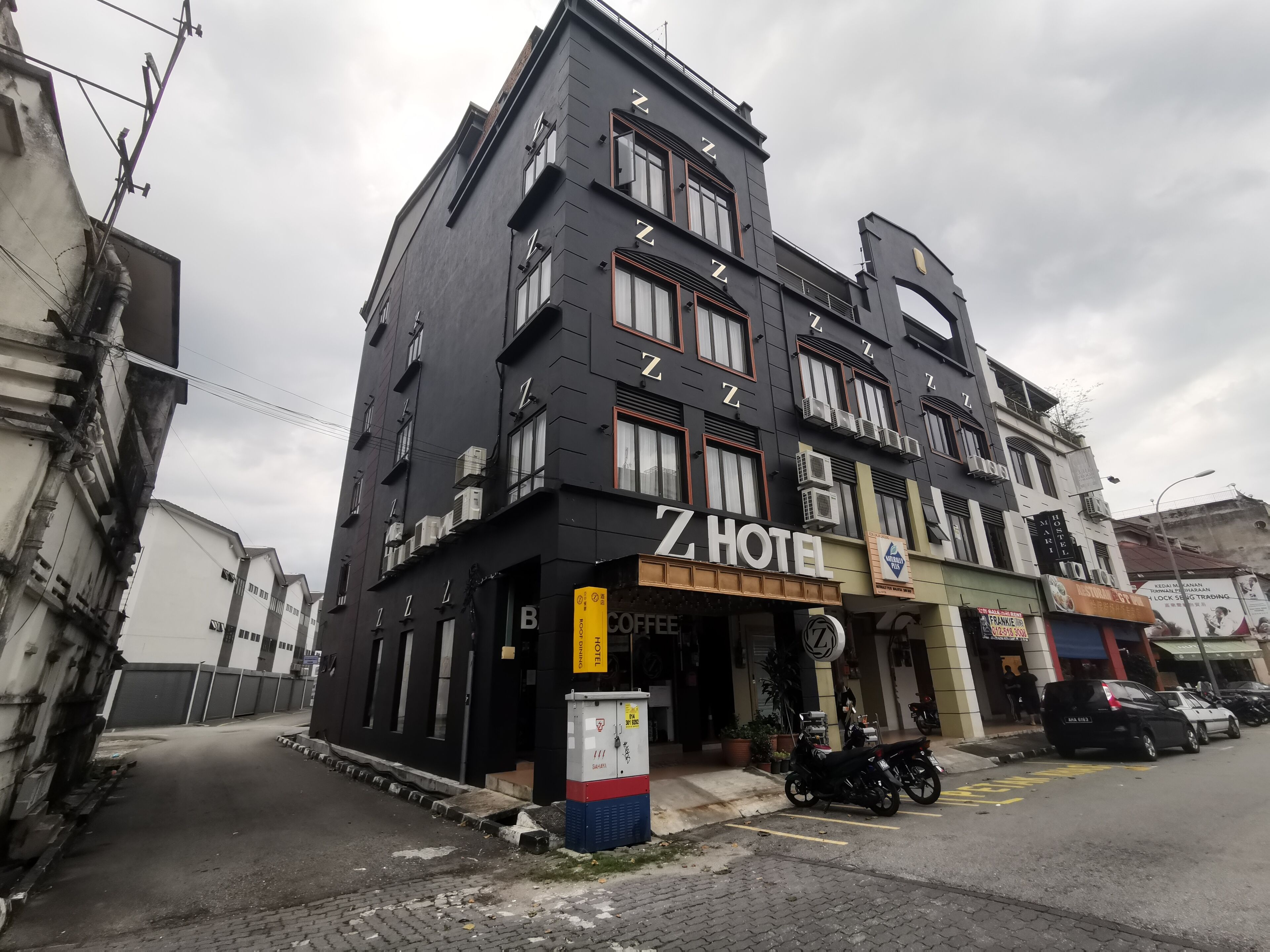 Un hotel con un llamativo letrero que dice 'Z HOTEL', una entrada visible y una motocicleta estacionada.