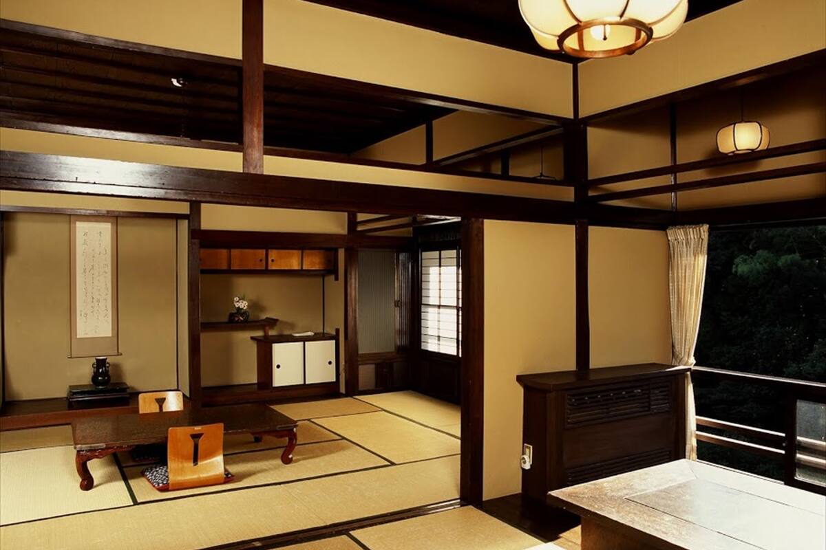 Um quarto japonês tradicional com tatames, uma mesa de madeira baixa, um armário e uma porta deslizante.