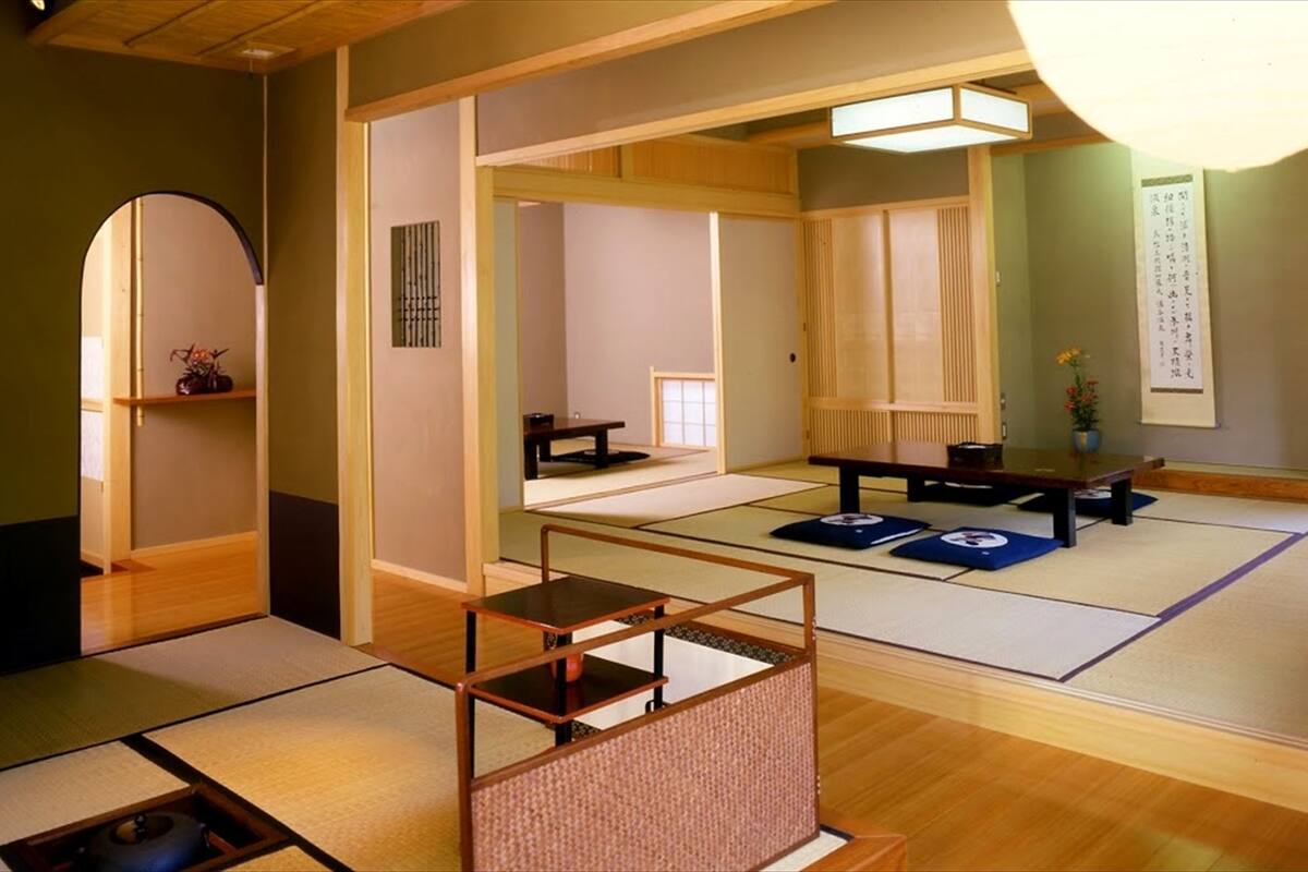 Um quarto japonês tradicional com tatames, um biombos shoji e uma mesa de madeira baixa.
