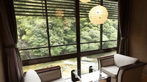 Una habitación con un ventanal amplio, un sofá, una mesa y una lámpara colgante.