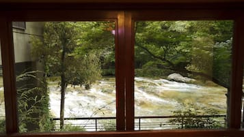 Vista de un río a través de una ventana con marco de madera, rodeada de exuberante vegetación.