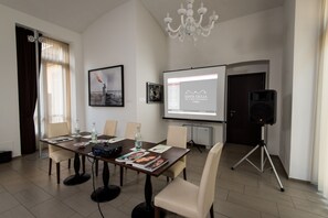 A conference room with a large table, chairs, a projector screen, and a speaker. - Santa Giulia Hotel e Residence (Turin)