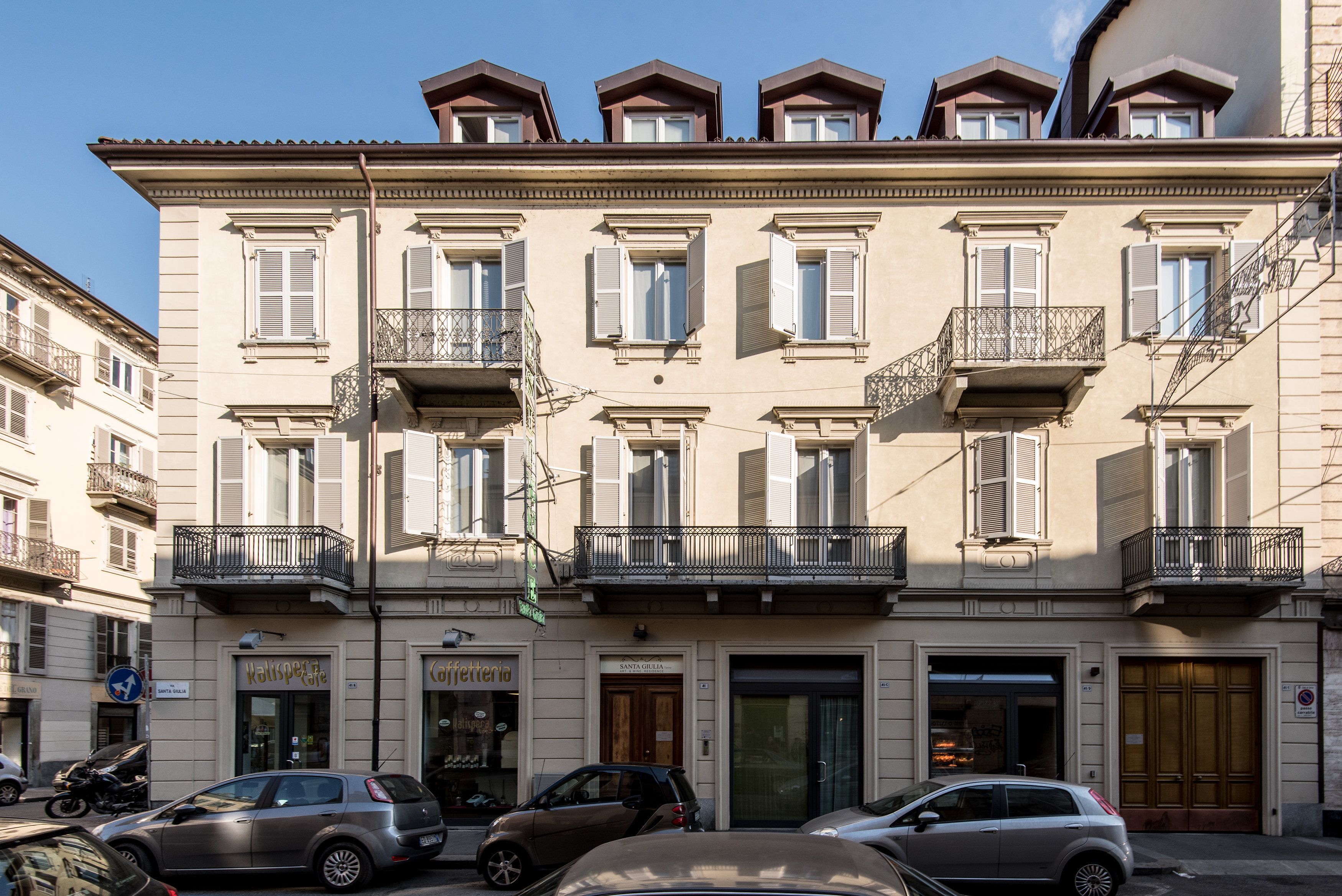 A multi-story building with balconies, a coffee shop, and a bakery on the ground floor.