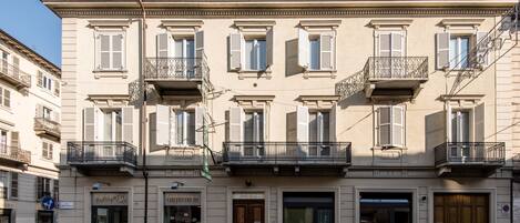 A multi-story building with balconies, a coffee shop, and a bakery on the ground floor.