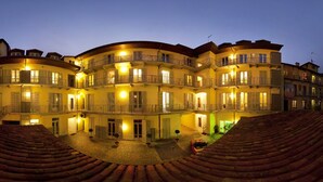 Un hotel de varios pisos con patio, balcones y tejado de tejas.