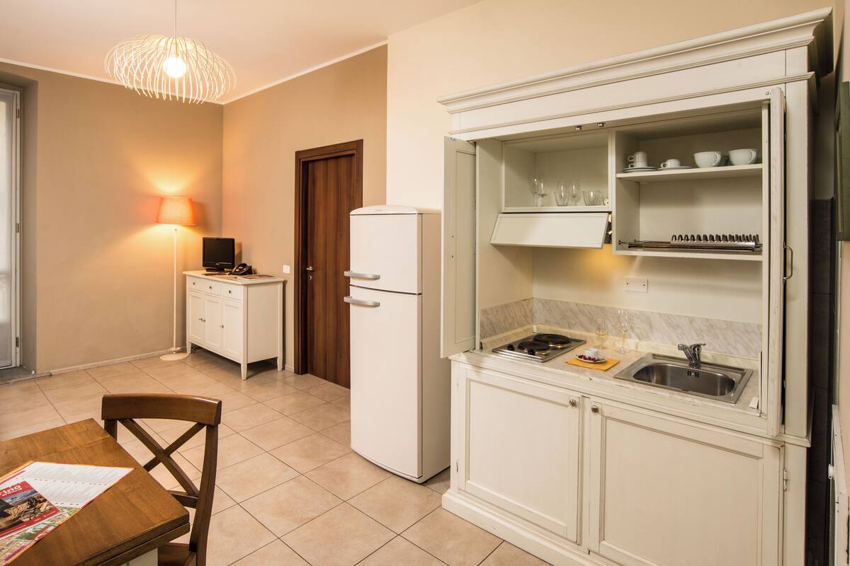 A compact kitchen with a refrigerator, a dining table with chairs, and a built-in oven.