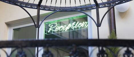A reception sign with a neon outline, a glass door, and a metal railing.