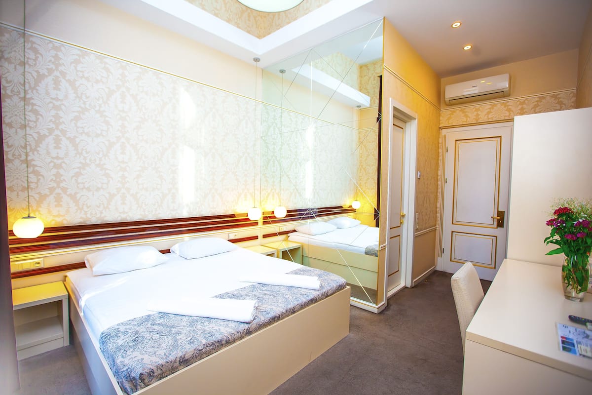 Ein Hotelzimmer mit einem großen Bett, Nachttischen, einem Schreibtisch und einem Spiegel.