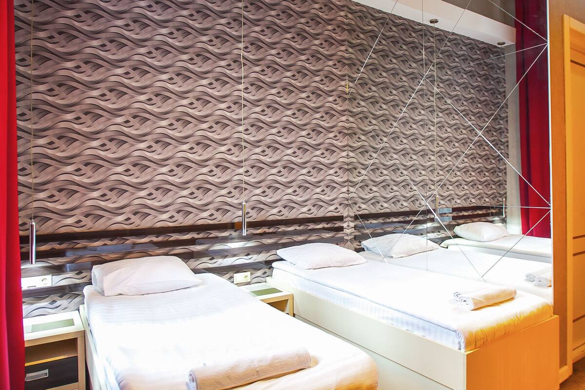 Ein Hotelzimmer mit zwei Betten, einer Wand mit Muster und einem modernen Kronleuchter.