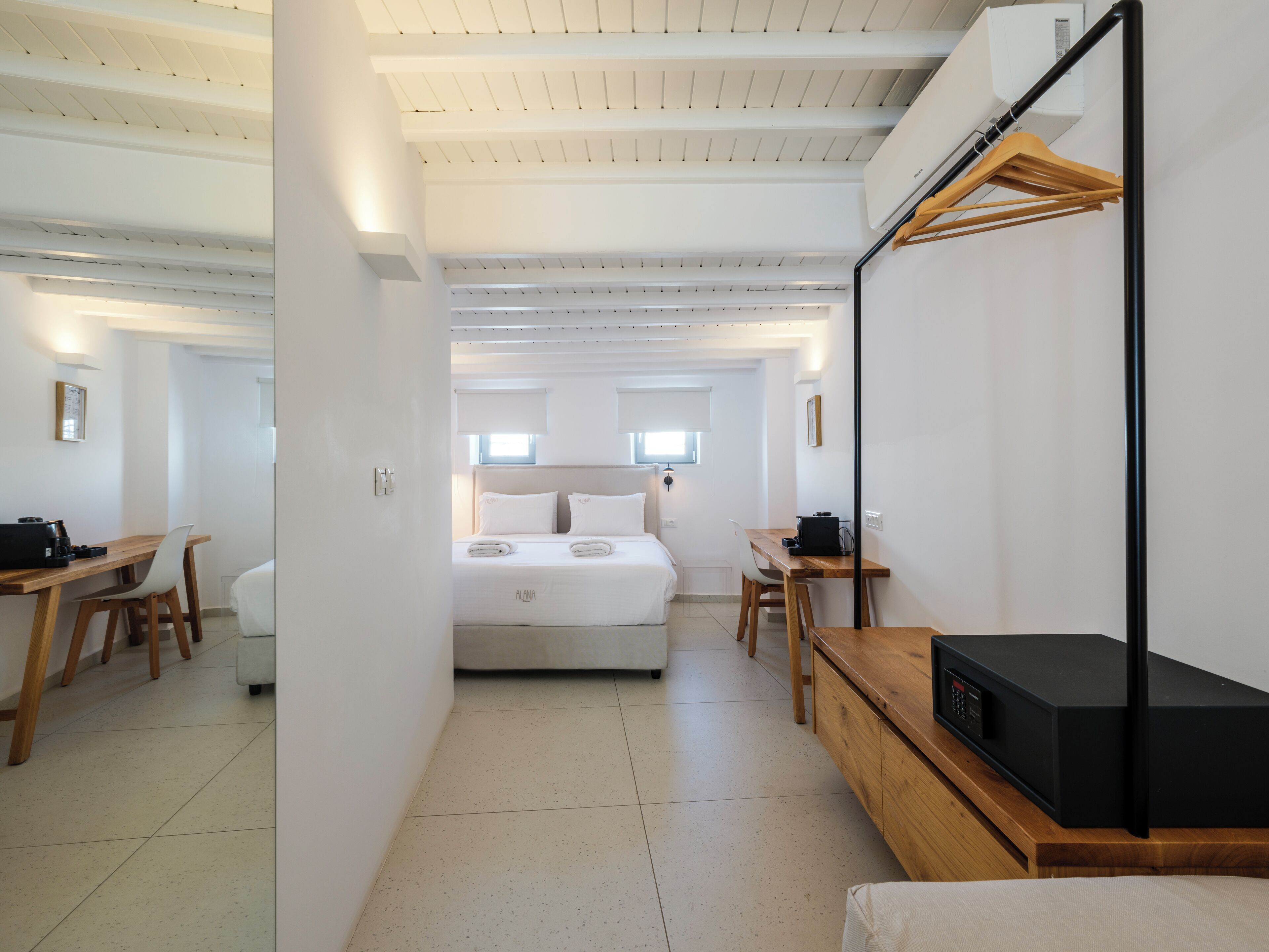 A modern hotel room with a bed, a desk, a chair, a TV, and a wardrobe.